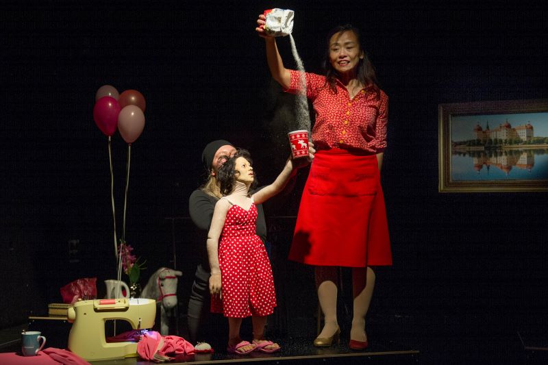 Frau schüttet Zucker in einen Becher einer Theaterfigur
